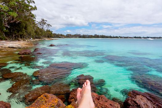 Relaxing on rocks in crystal clear waters, a beach paradise, yachts and boats moored offshore