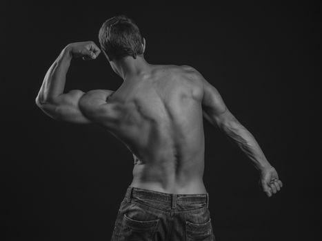 Muscular athlete flexing his arm demonstrating biceps with his back to the camera
