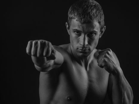 Young shirtless fit fighter doing shadow boxing