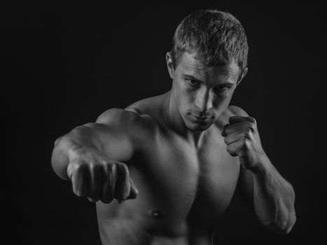 Young shirtless fit fighter doing shadow boxing