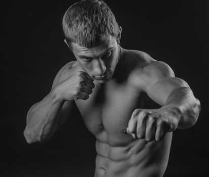 Young shirtless fit fighter doing shadow boxing