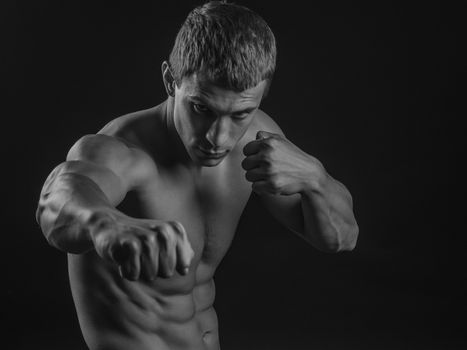 Young shirtless fit fighter doing shadow boxing