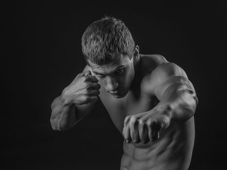 Young shirtless fit fighter doing shadow boxing