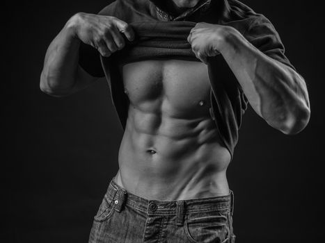 Young man pulls up his shirt to expose perfect abs
