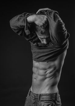 Young man pulls up his shirt to expose perfect abs