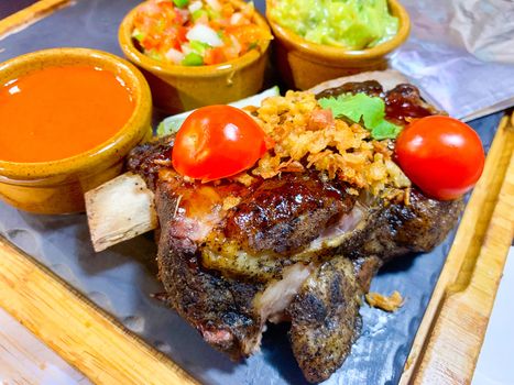 Delicious plate of ribs, guacamole, salad, sauces and tomatos
