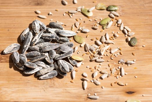 Healthy seeds of sunflower, sesame and pumkin placed over a light colour wooden table.