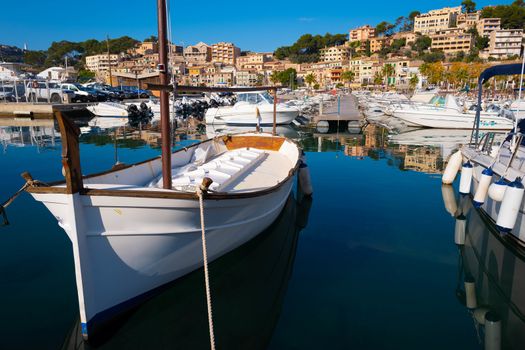 Small white boat anchored in the harbor surrounded by other boats.