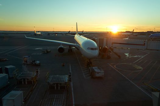 Top down view of a docked plane at airport on sunset with the golden light of the sun warming the scene.