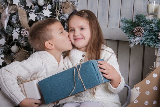 Boy kissing happy girl on cheek with Christmas gift 