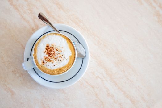 Cappuccino on a cup with foam and spoon,view from above.