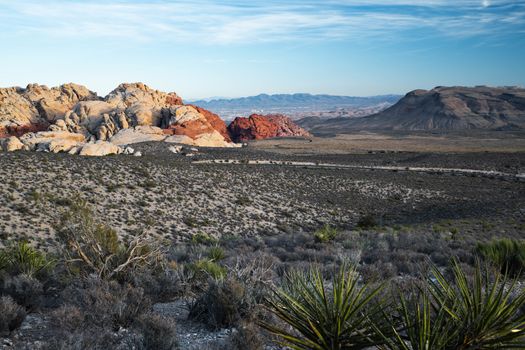 A view of the road crossing the Red Rock Canyon with the red rocks in the background.