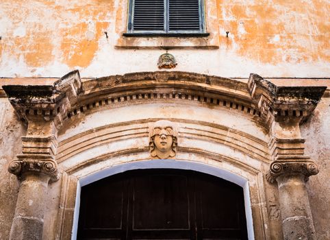 Gothic detail. Young woman portrait at the entrance of a 200 years old building in Ciutadella town, Menorca (Spain)