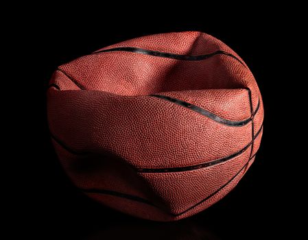 Deflated old basketball on black background. Reflection.