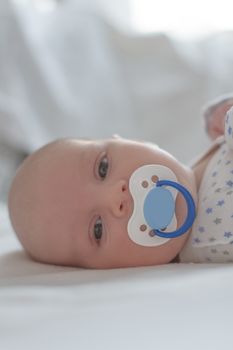 Close-up of baby boy with dummy on white