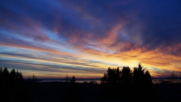 Horizontal silhouette of sunset forest landscape background. Evening sunset with beautiful pink picturesque clouds. dark sunset with crimson clouds in sun beams.