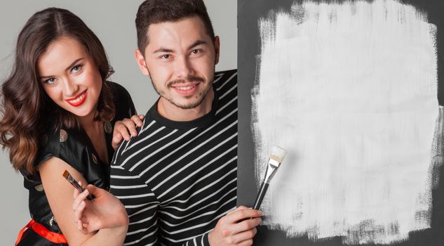 Couple with paint brushes and picture with white blank copy space