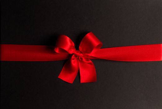 Red gift bow on black background