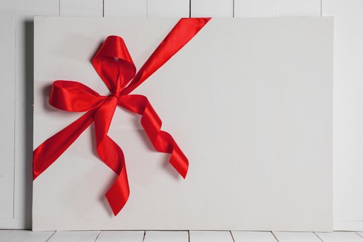 Decorative red ribbon and bow on a background of white painted rustic board with copyspace