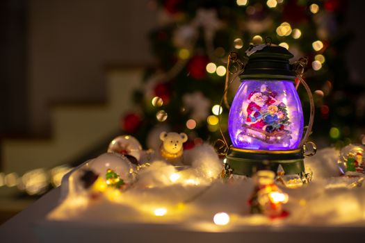 Christmas decoration, snow dome, globe with table decoration, Santaclaus on sleigh with child in winter scene, christmas tree with lights in background, selective focus