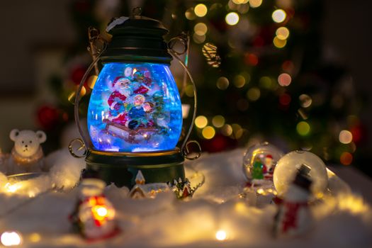 Christmas scene, Santa with child on a sleigh in snow dome with reindeer, polar bears and snowmen domes and candles, illuminated christmas tree in background, selective focus