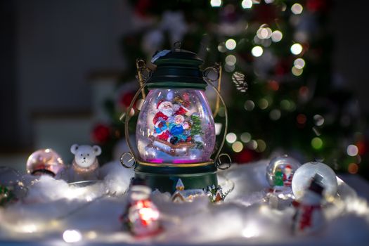 Christmas scene, Santa with child on a sleigh in snow dome with reindeer, polar bears and snowmen domes and candles, illuminated christmas tree in background, selective focus