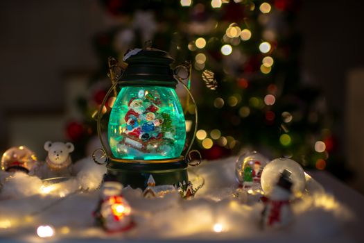 Christmas scene, Santa with child on a sleigh in snow dome with reindeer, polar bears and snowmen domes and candles, illuminated christmas tree in background, selective focus