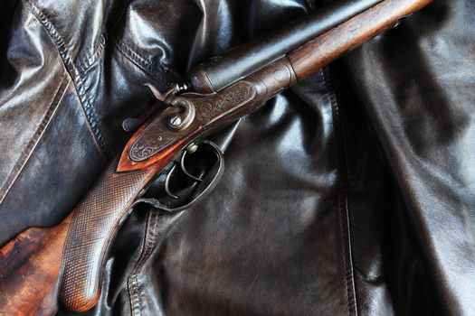 Ancient hunting shotgun closeup on leather background