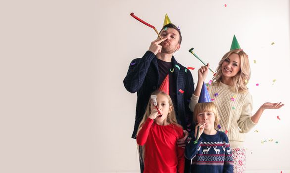 Family blowing party trumpets with confetti celebrating new year