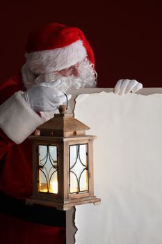 Santa Claus with lantern holding vintage paper billboard with copy space for text