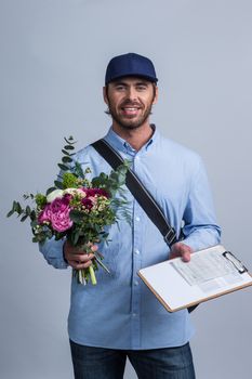 Delivery man holding flower bouquet and form