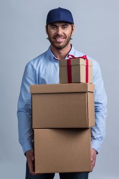 Happy smiling delivery man in uniform cap holding box stack