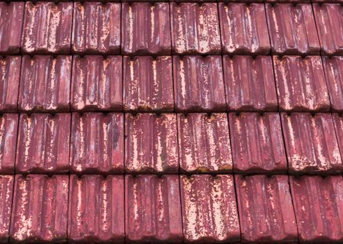 old and weathered red stone roof tiling in macro closeup with faded out colors, a architecture texture background