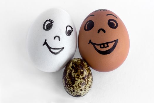 Funny eggs imitating a happy mixed family with versicolored baby on white background