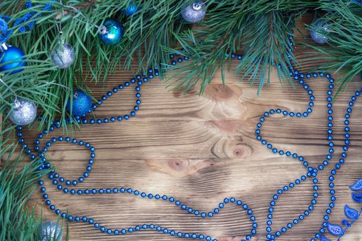 Christmas and New Year wooden background with fir tree acerose, blue and silver balls and garland ornament decoration, copy space