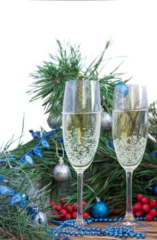 Christmas and New Year still life composition with two champaign glasses, pine tree acerose, red rowan berries, blue and silver balls, garland ornament decoration, copy space