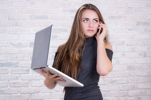 Young beautiful girl model with long hair imitates business lady, office manager or administrator with notebook and telephone