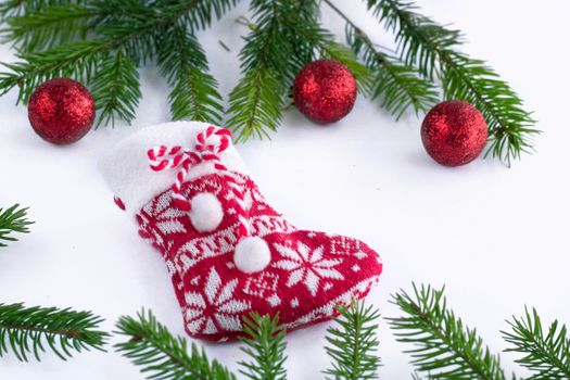 Red Christmas stocking sock and decoration balls on white background, green contiferous fir tree branches
