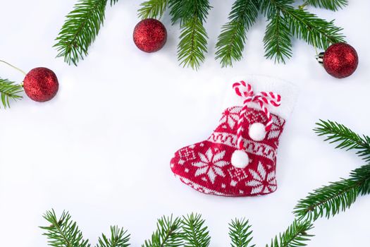 Red Christmas stocking sock and decoration balls on white background, frame of green contiferous tree branches