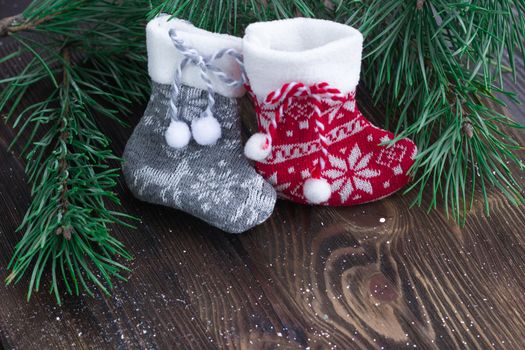 Christmas composition of two knitted socks and xmas tree branches on wooden background