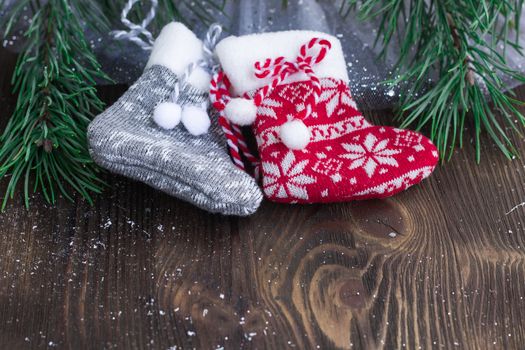 Christmas composition of two knitted socks and xmas tree branches on wooden background