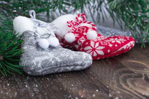 Christmas composition of two knitted socks and xmas tree branches on wooden background