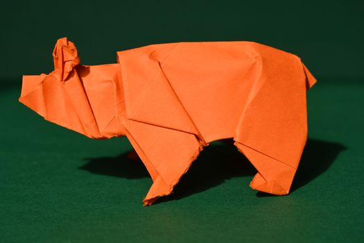 Orange origami paper bear on green background