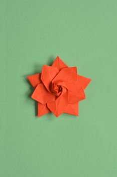 Red origami paper star on green background