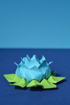 Blue origami paper water lily flower on blue background