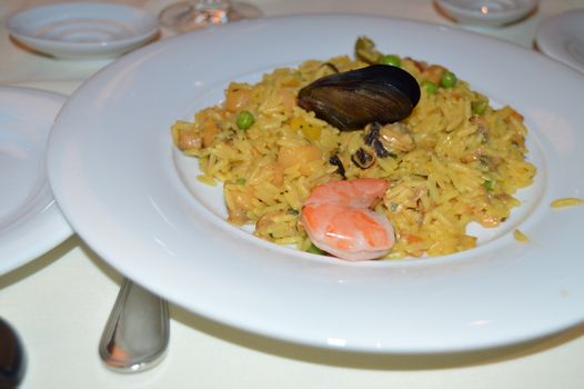 Close-up of traditional Spanish paella with seafood on a white plate, selective focus.