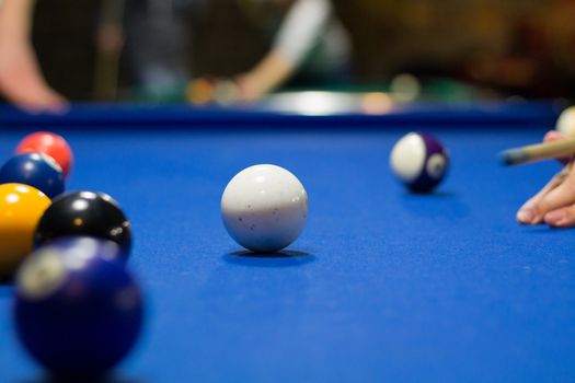 Billiard pool game in progress, player aims to shoot balls with cue