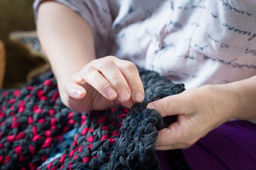 Close-up of elderly lady doing sewing hand work with needle and thread