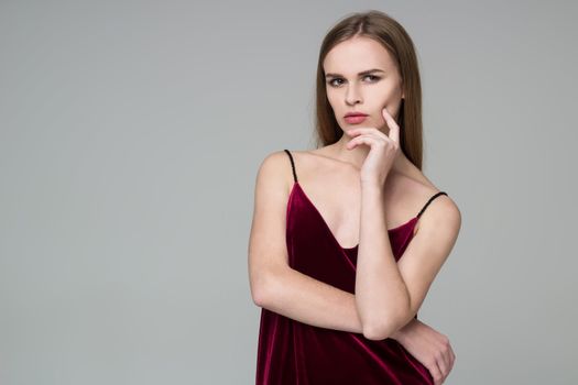 Young model long-haired blond girl in dard red dress poses showing emotions