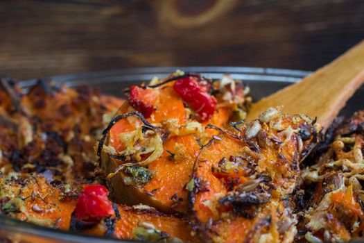 Vegetarian dish of orange pumkin, mixed vegetables, herbs and cheese baked in oven